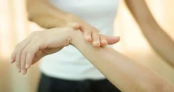 Test musculaire en kinésiologie — main posée sur le poignet pour évaluer la réponse du muscle